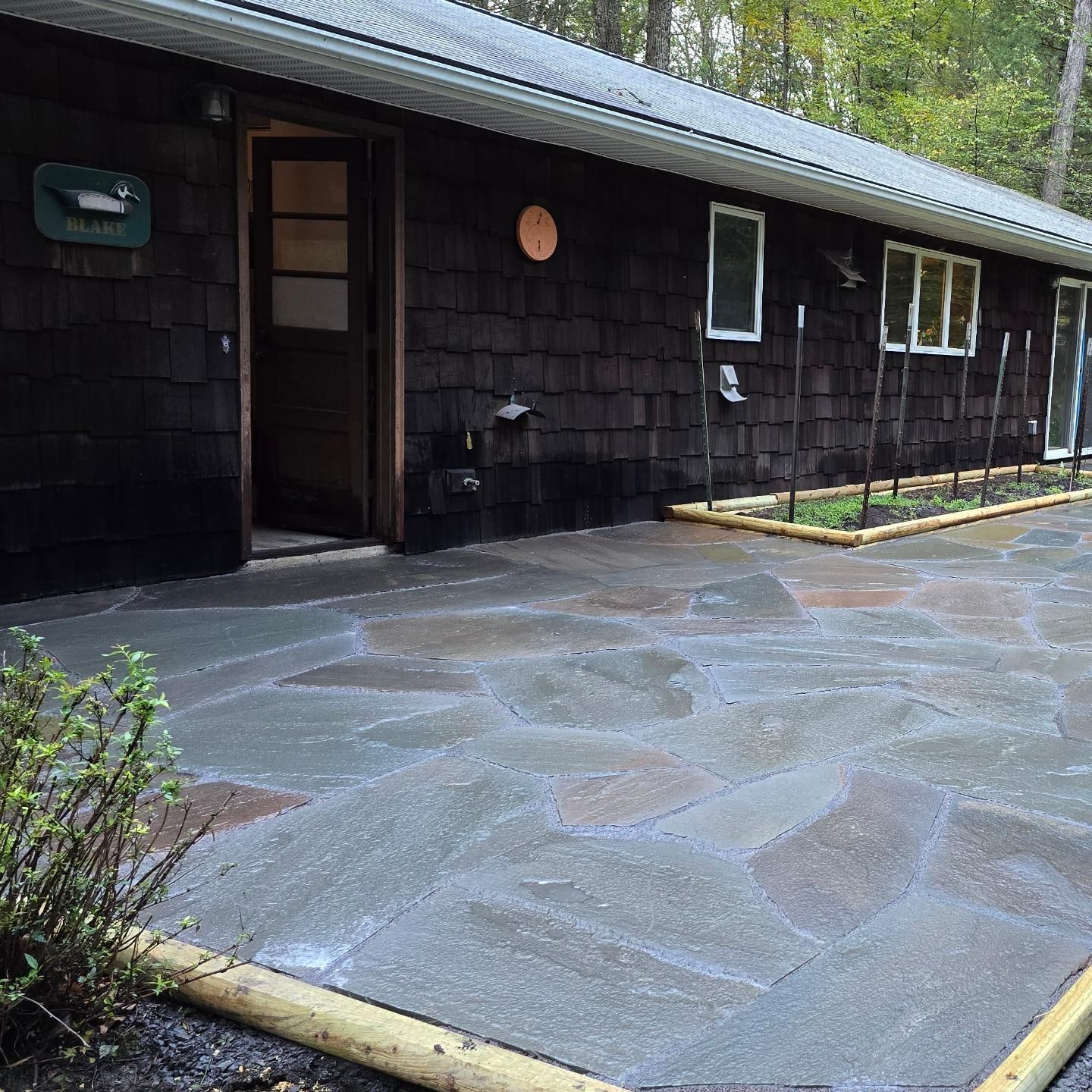 A black house with a patio in front of it