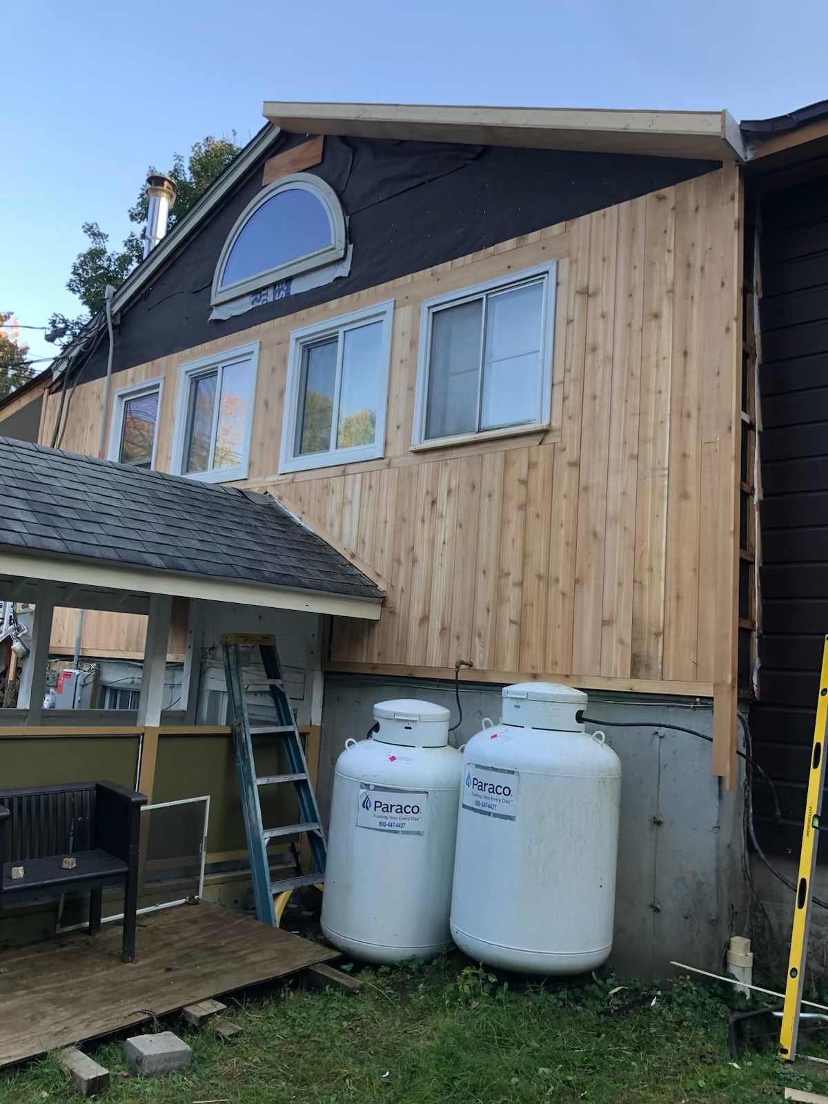 Two propane tanks are sitting in front of a house under construction.
