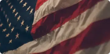 A close-up, angled view of a waving American flag with its distinctive red, white, and blue colors.