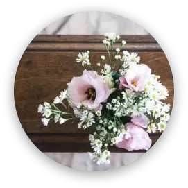 A small bouquet of pink lisianthus and white baby's breath flowers resting on a wooden casket.