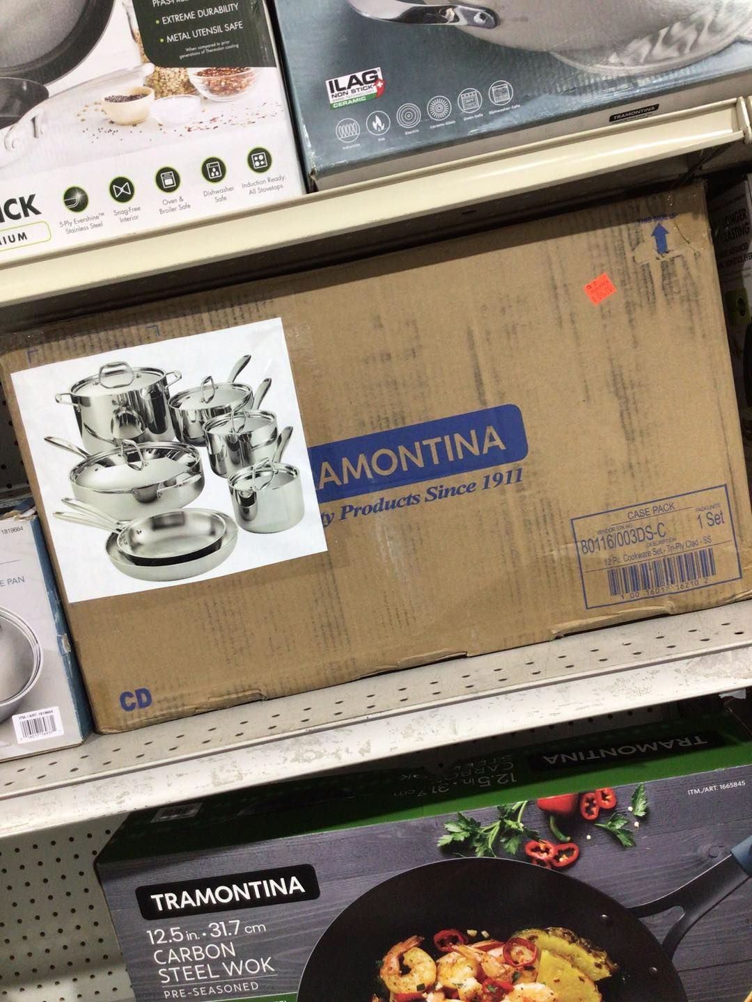 A box of pots and pans is on a shelf in a store.