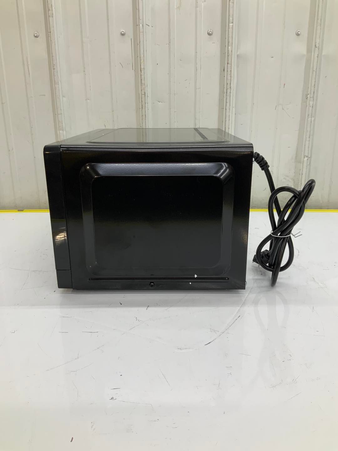 A black microwave oven is sitting on top of a white table.