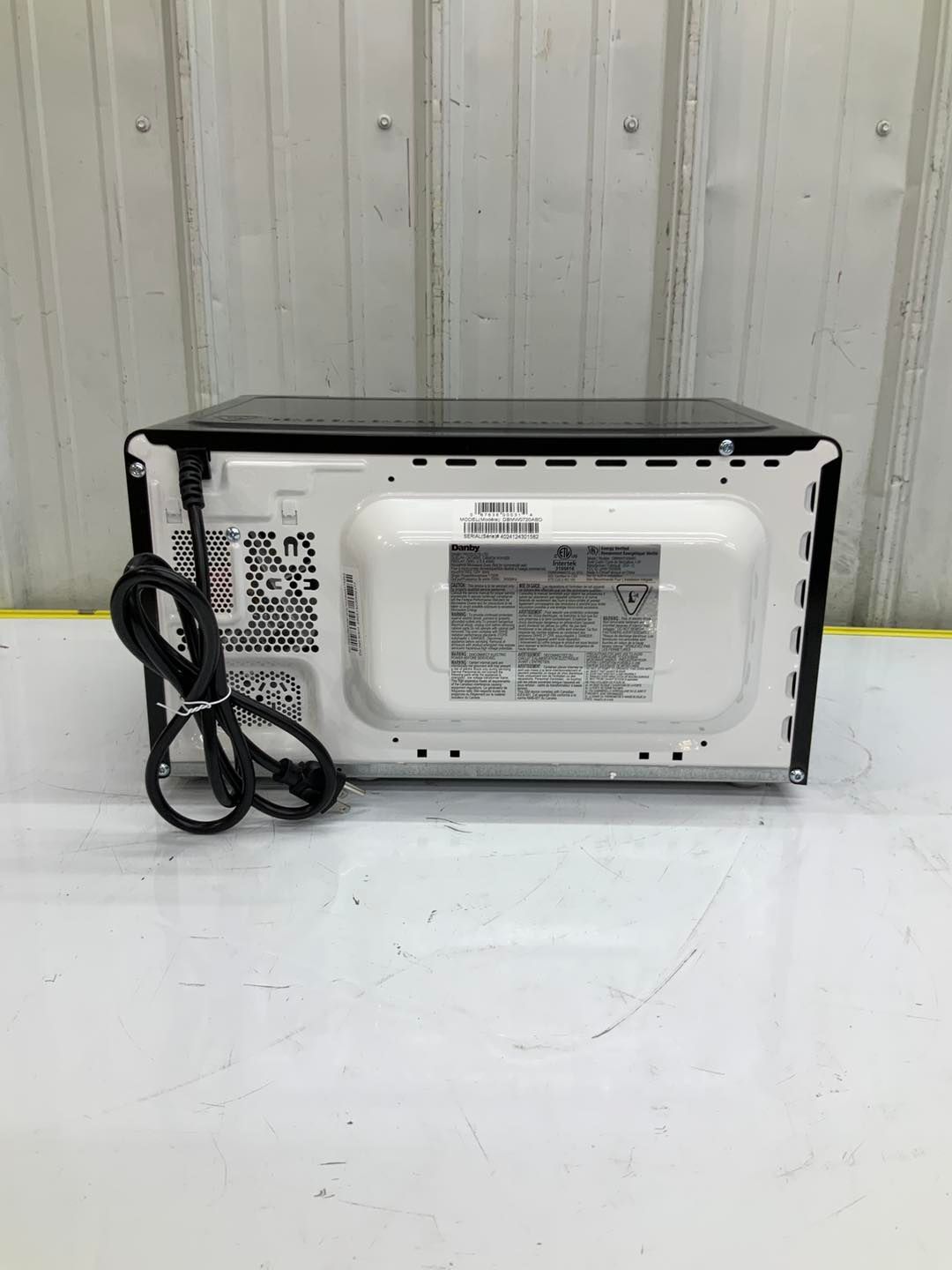 A microwave oven is sitting on top of a white table.