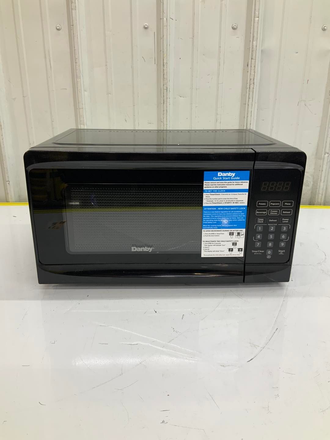 A black microwave oven is sitting on top of a white table.