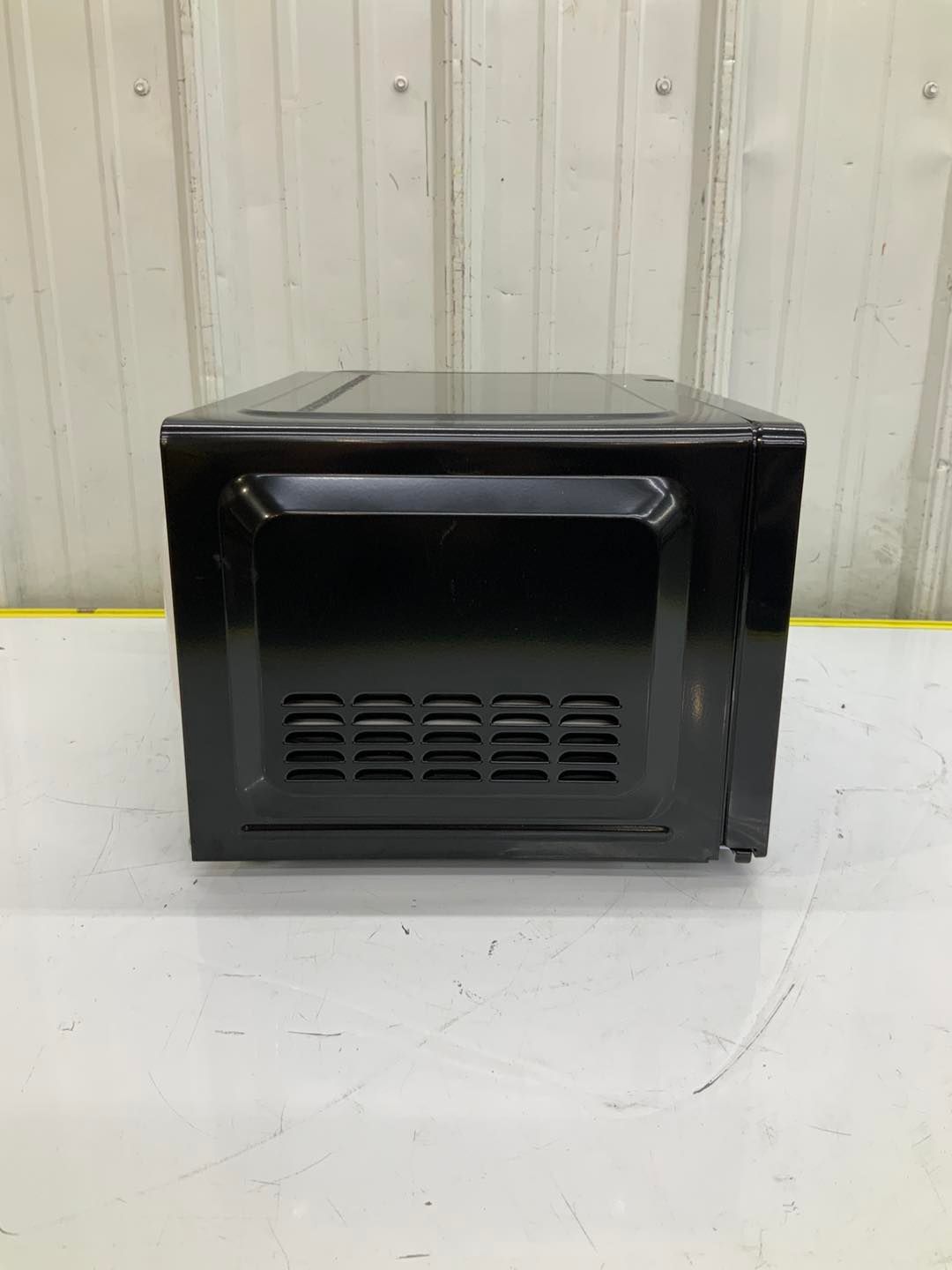 A black microwave oven is sitting on top of a white table.