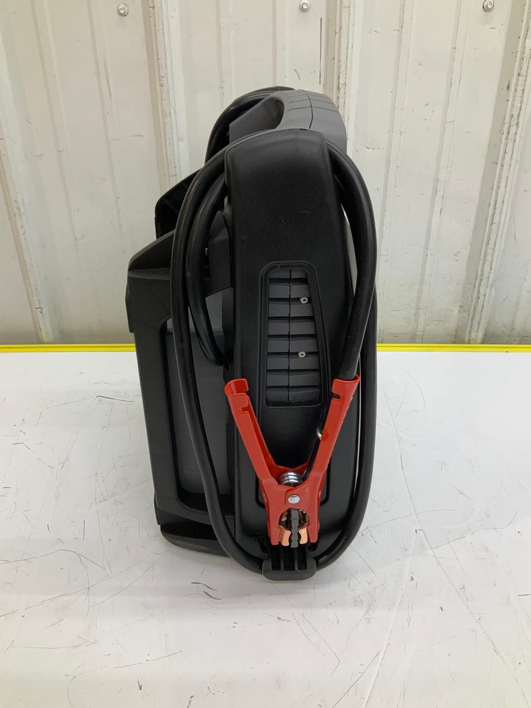 A black device with red clamps attached to it is sitting on a table.