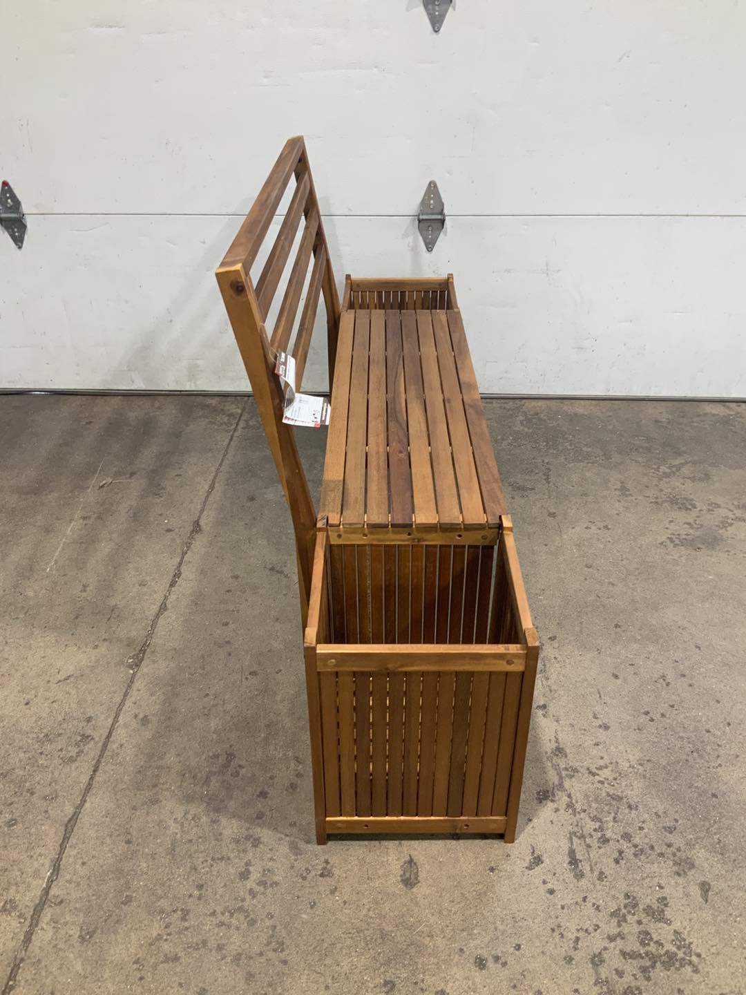 A wooden bench with a planter underneath it is sitting in front of a garage door.