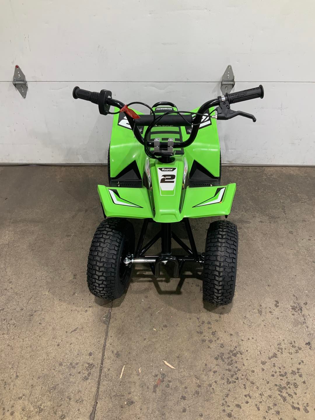 A green atv is parked in front of a garage door.