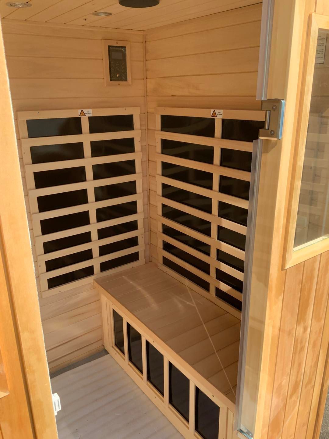 A wooden sauna with black windows and a bench.
