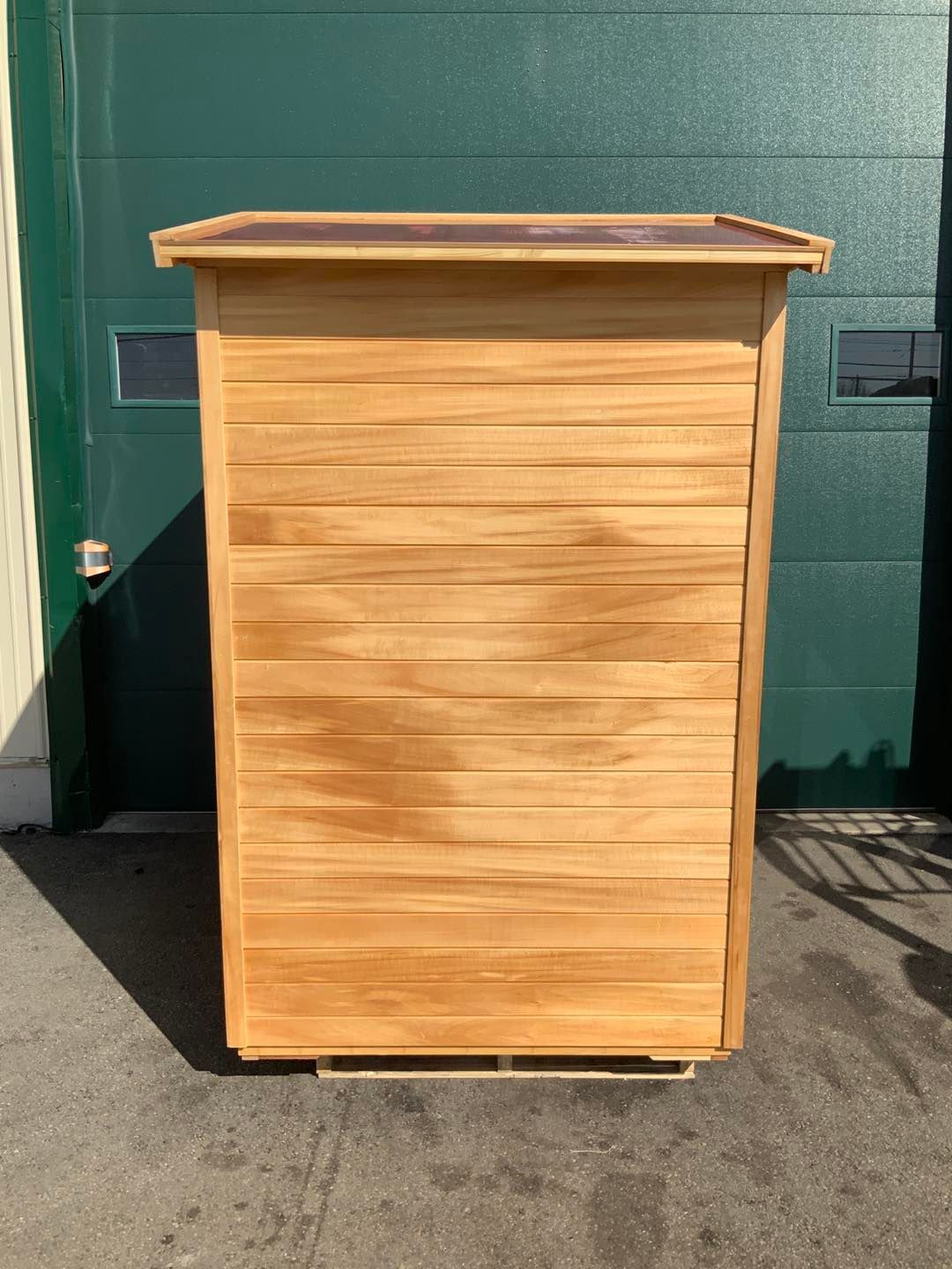 A wooden box is sitting in front of a green garage door.