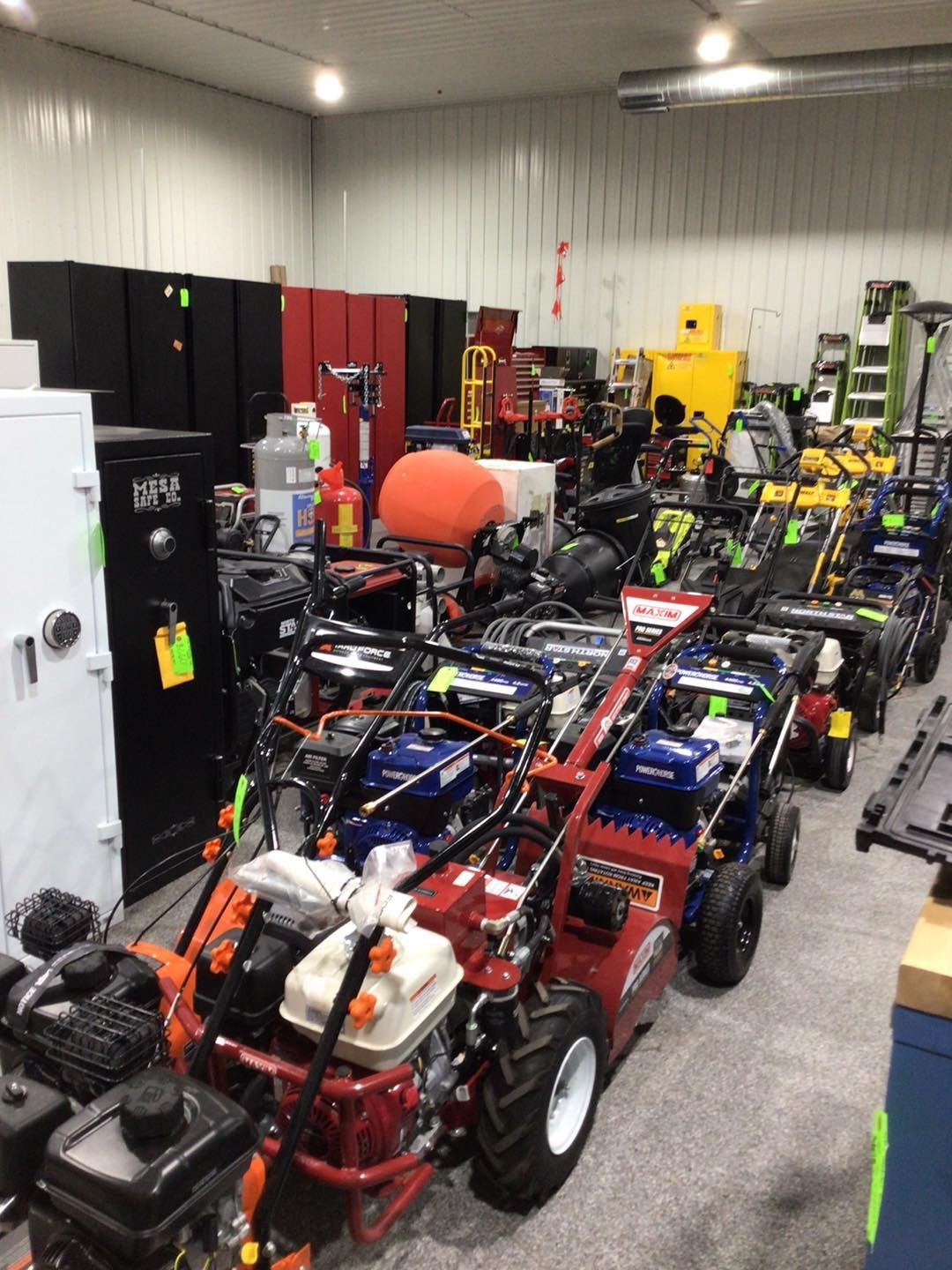 A large room filled with lots of lawn mowers and snow blowers.