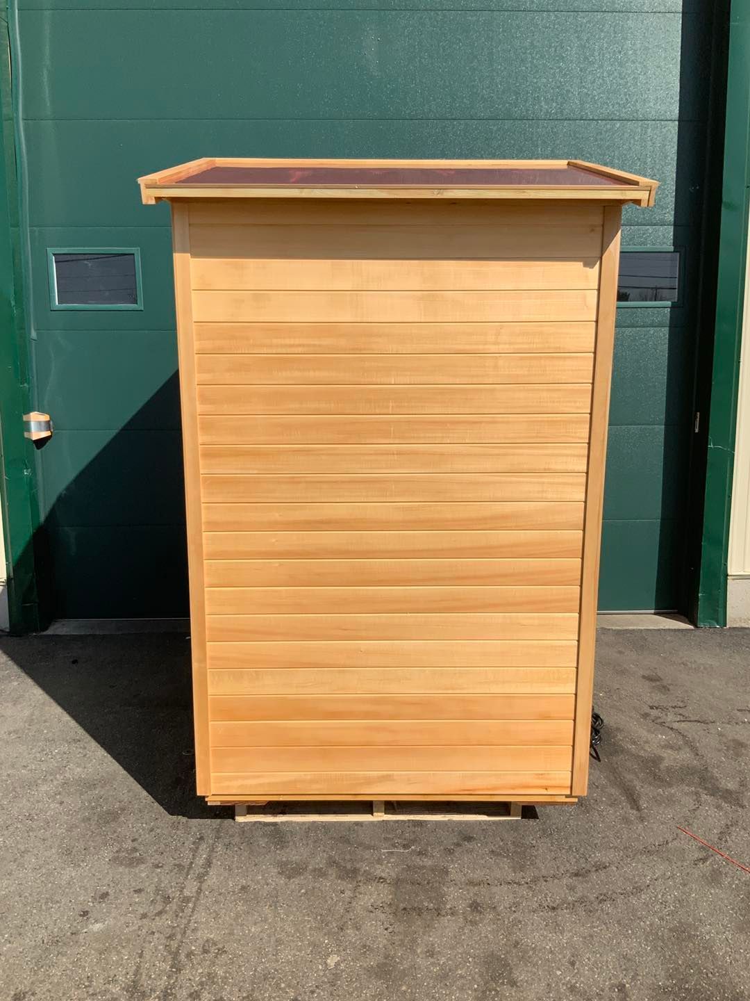 A wooden shed is sitting in front of a green garage door.