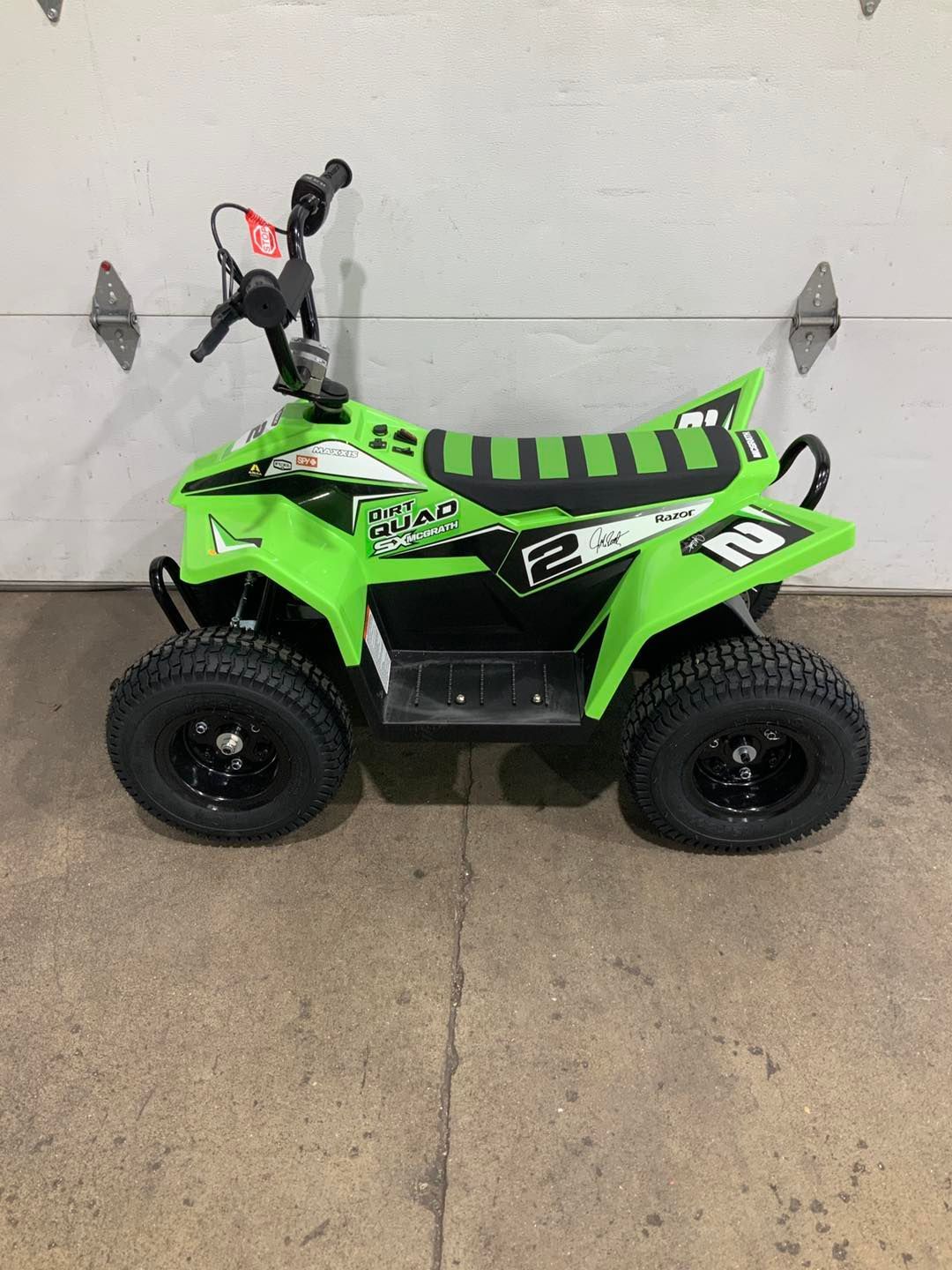 A green atv is parked in front of a garage door.