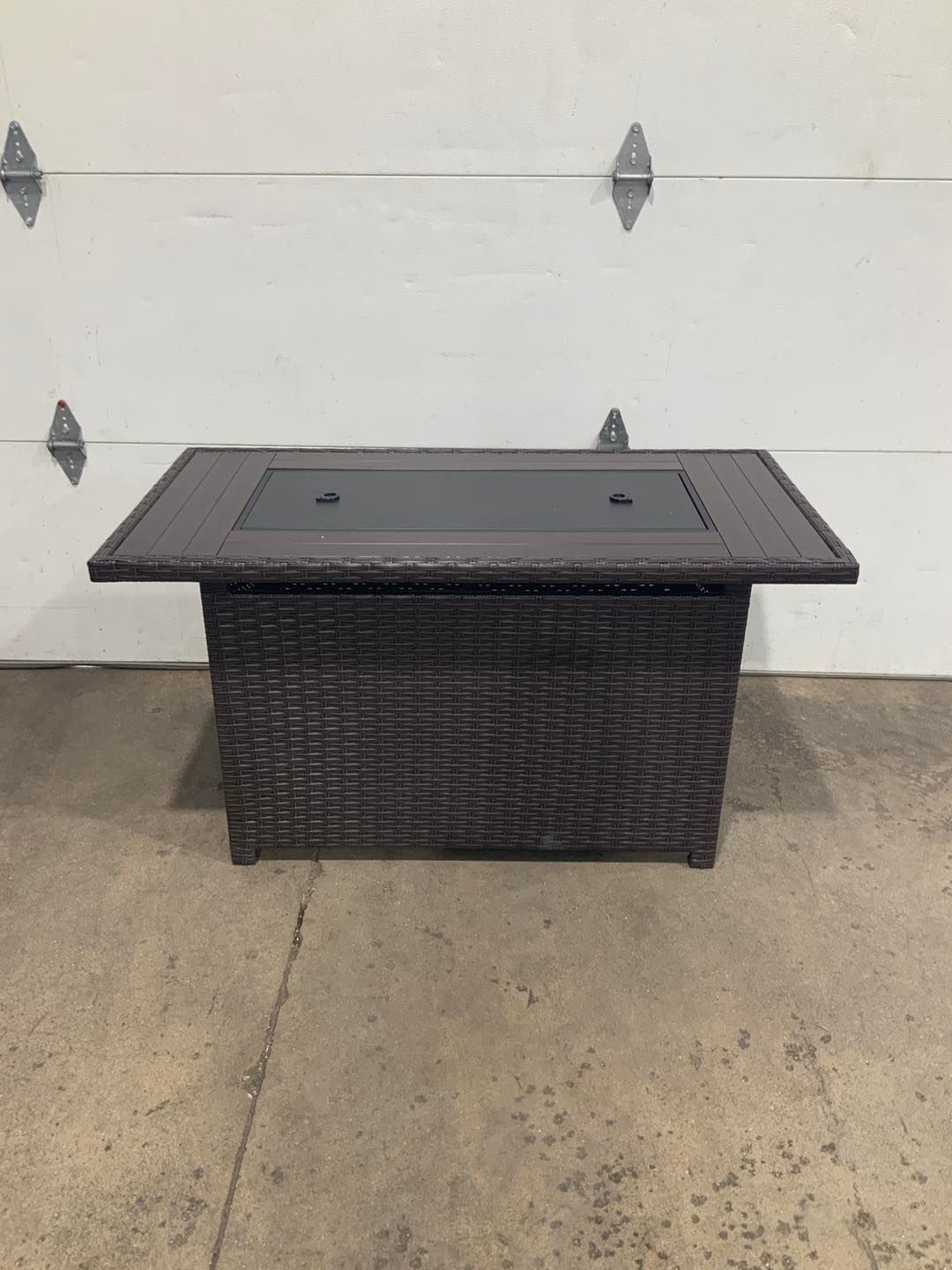 A wicker coffee table is sitting in front of a garage door.