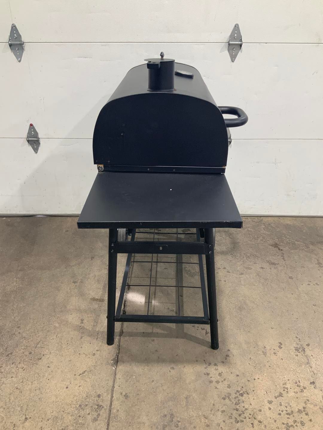 A black grill is sitting in front of a garage door