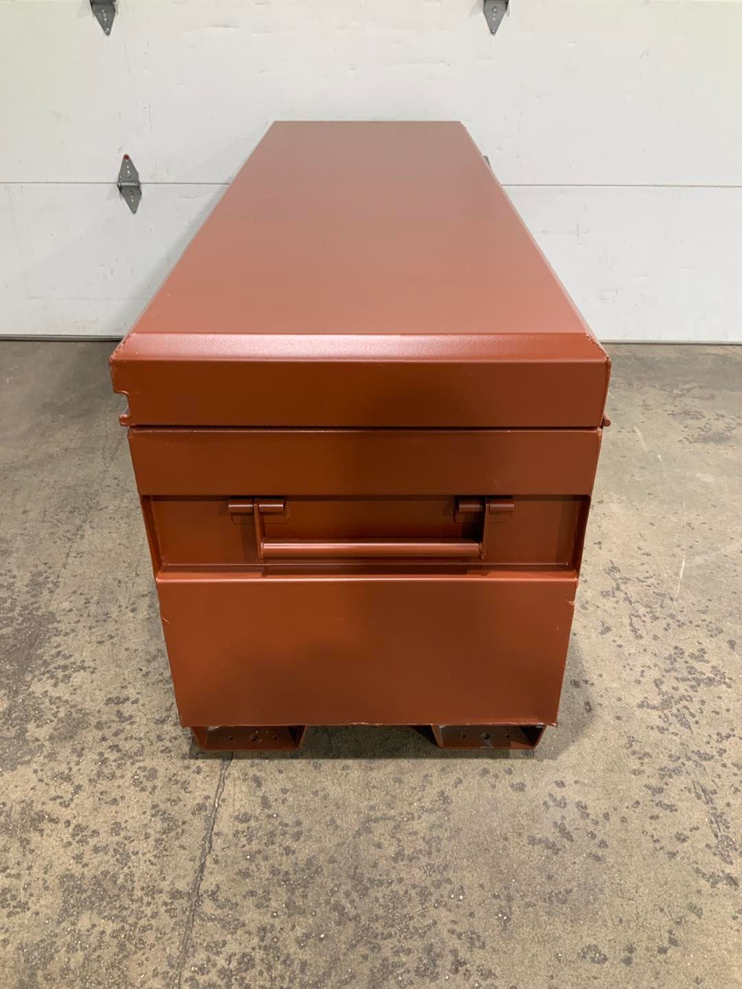 A red box with a handle is sitting in front of a garage door