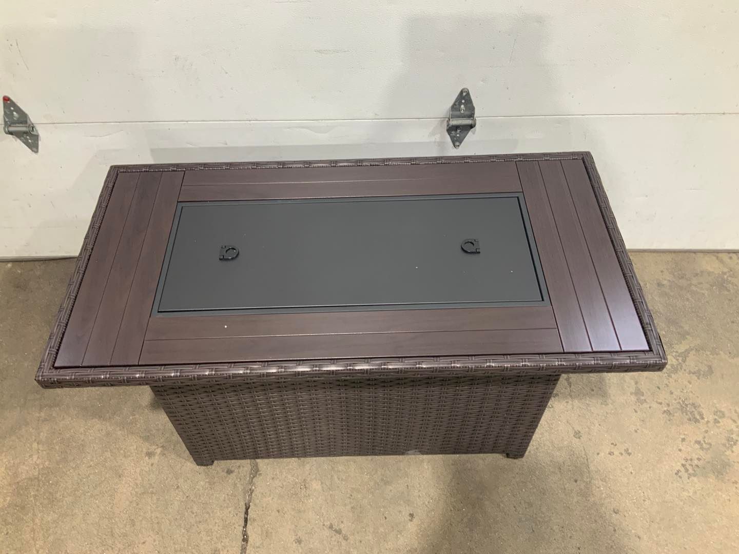 A wicker coffee table with a glass top is sitting in front of a garage door.