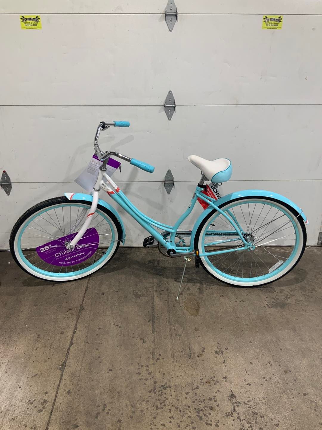 A blue and white bicycle is parked in front of a garage door.