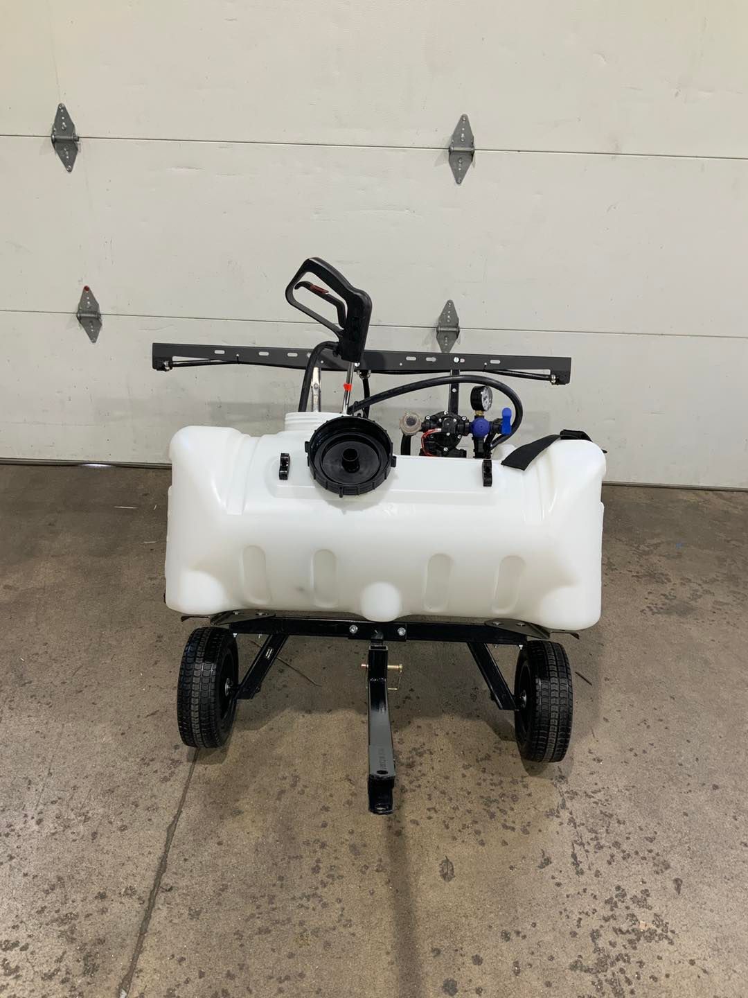 A white wagon with wheels is sitting in front of a garage door.