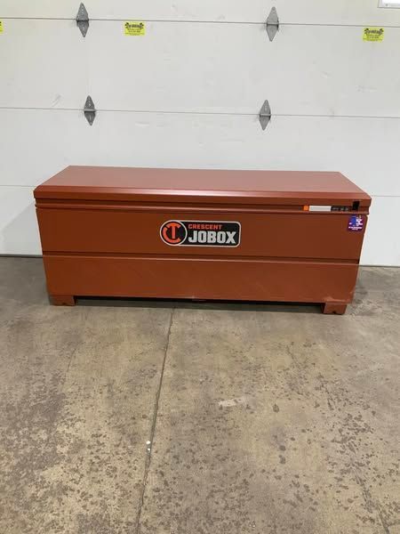 A red toolbox is sitting in front of a garage door.