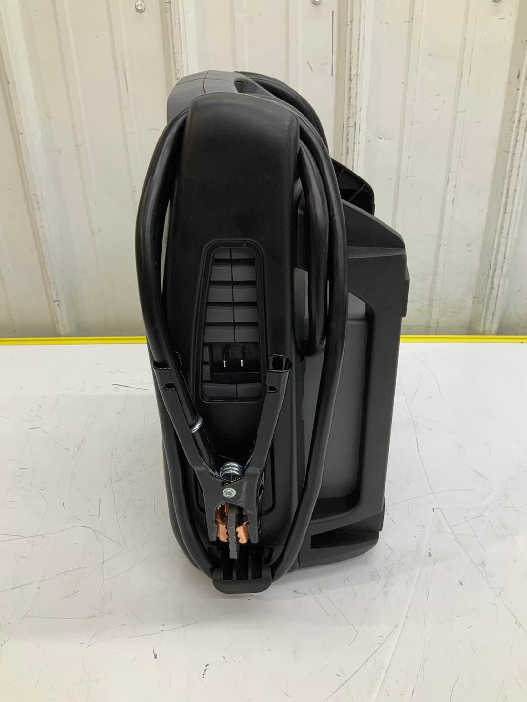 A black battery charger is sitting on top of a white table.