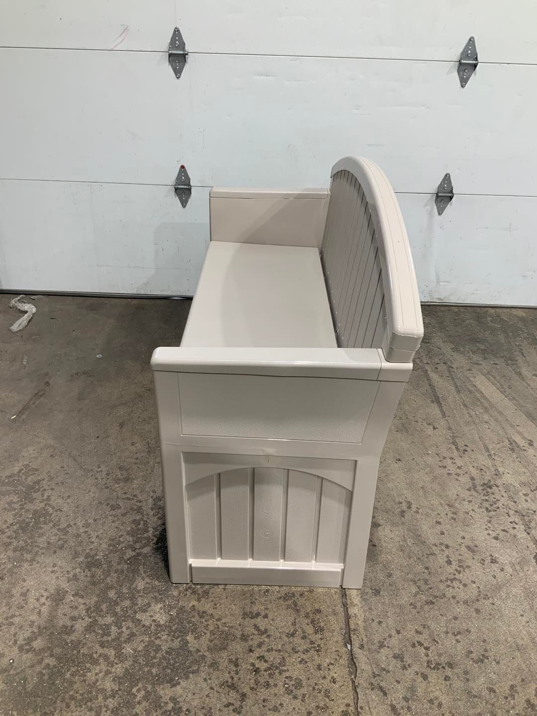 A white bench is sitting in front of a garage door.