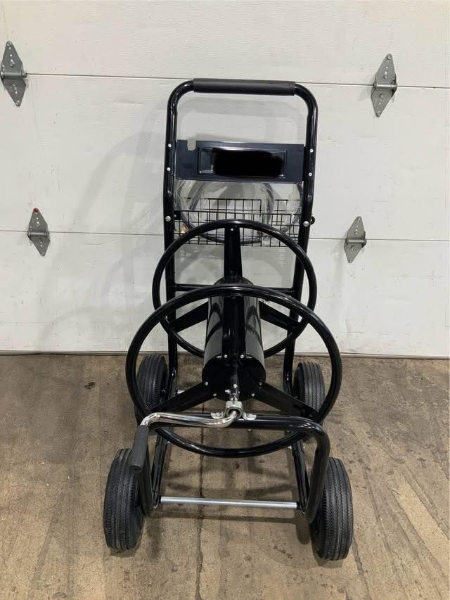 A hose reel cart is sitting in front of a garage door.