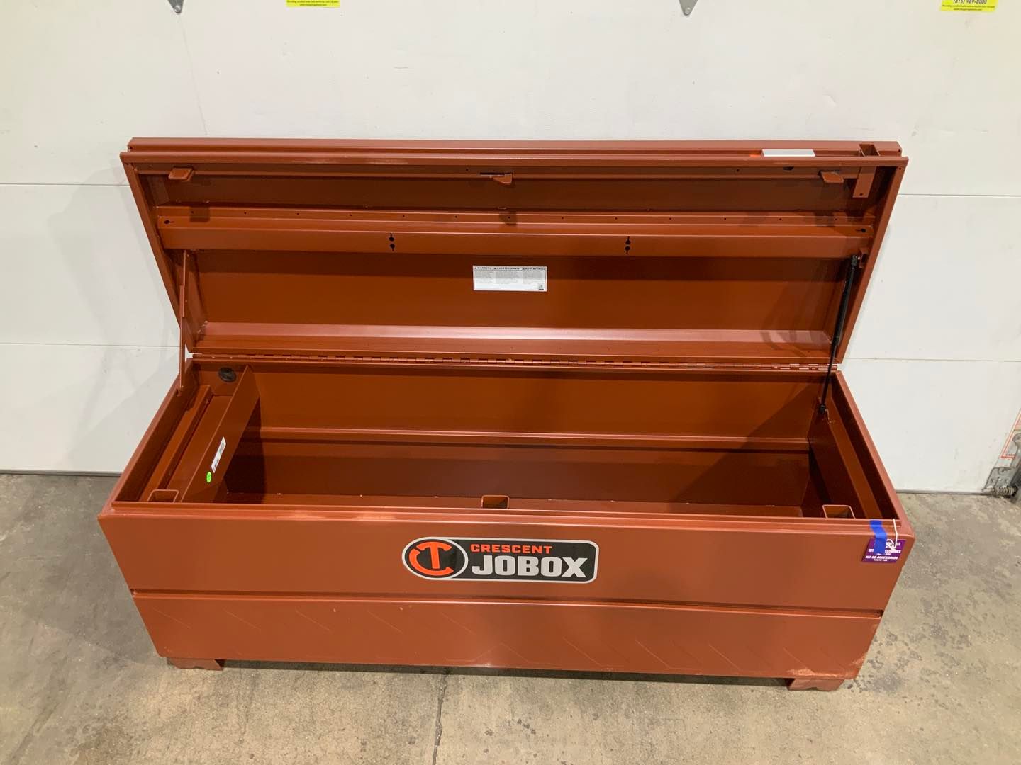 A red toolbox with the lid open is sitting on a concrete floor.