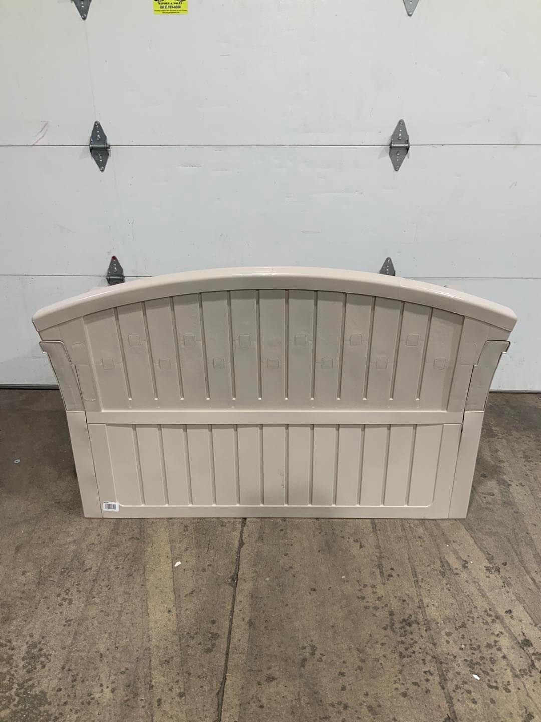 A white bench is sitting in front of a garage door.