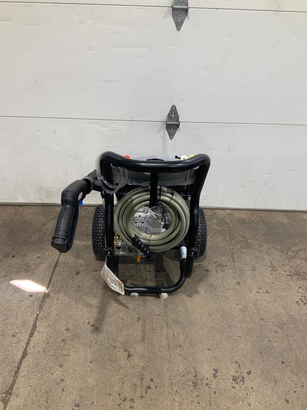 A pressure washer is sitting in front of a garage door.
