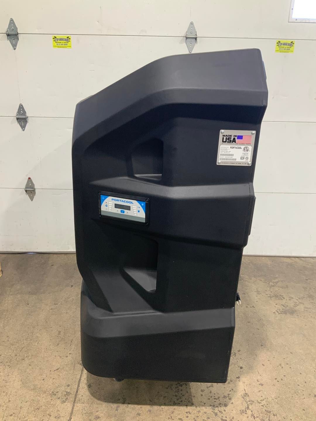 A large black box is sitting in front of a garage door.