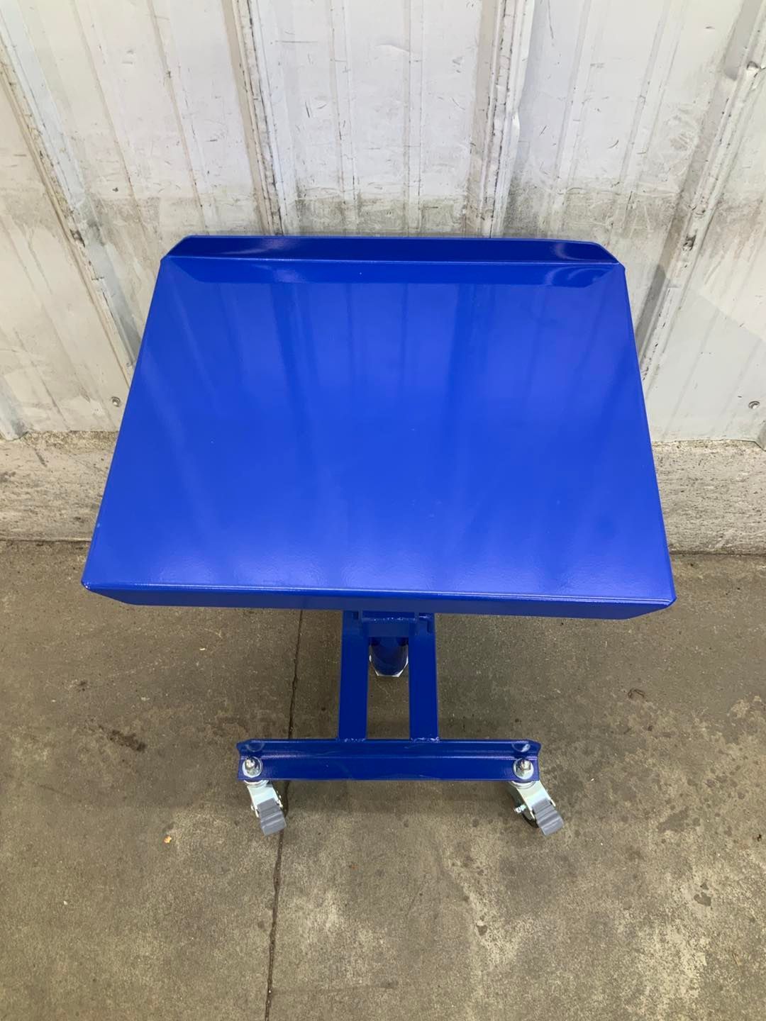 A blue table with wheels is sitting on the ground.