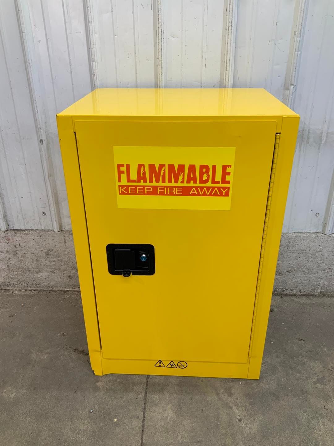 A yellow flammable cabinet is sitting on the sidewalk in front of a building.