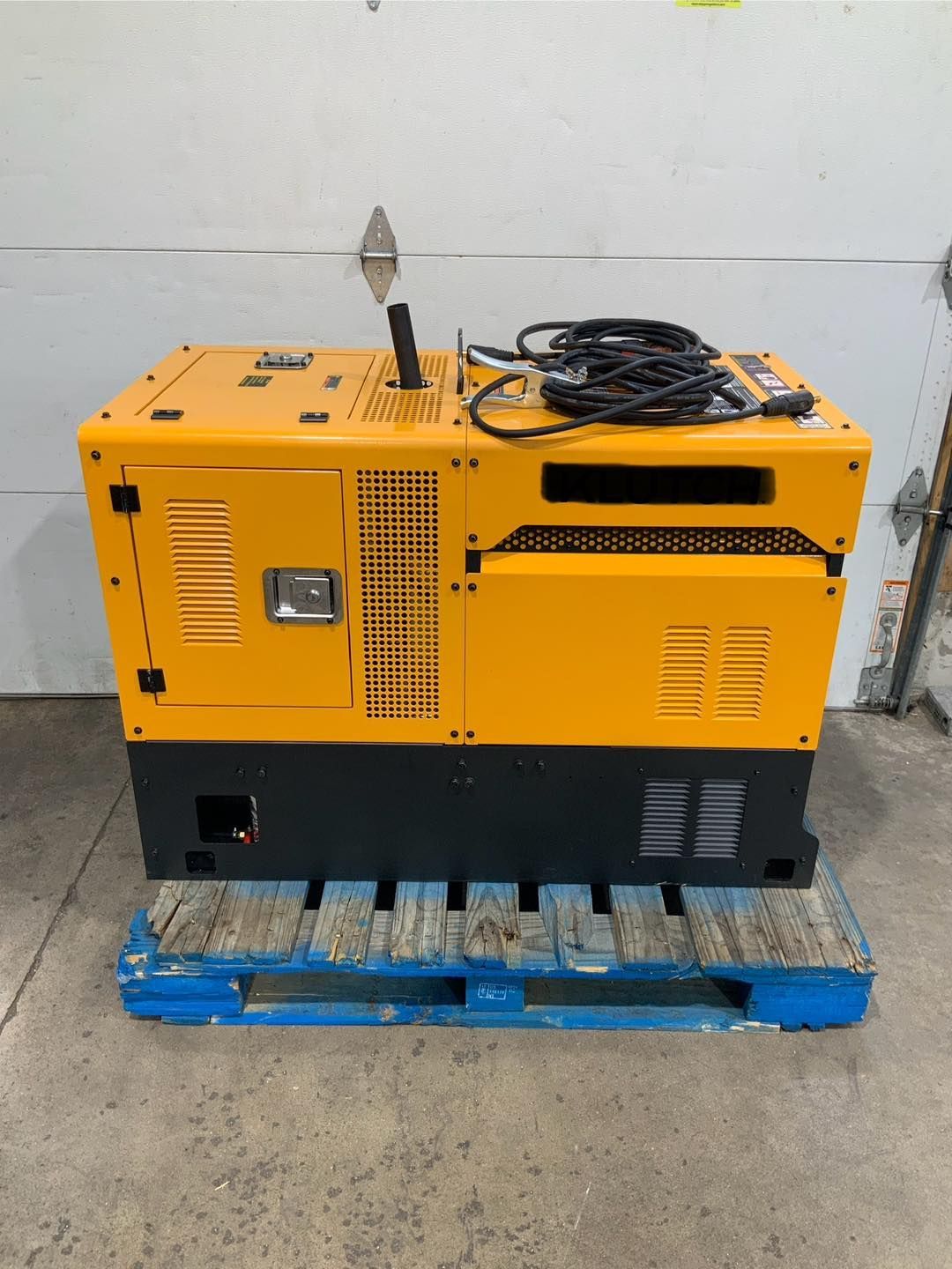 A yellow generator is sitting on top of a blue pallet.