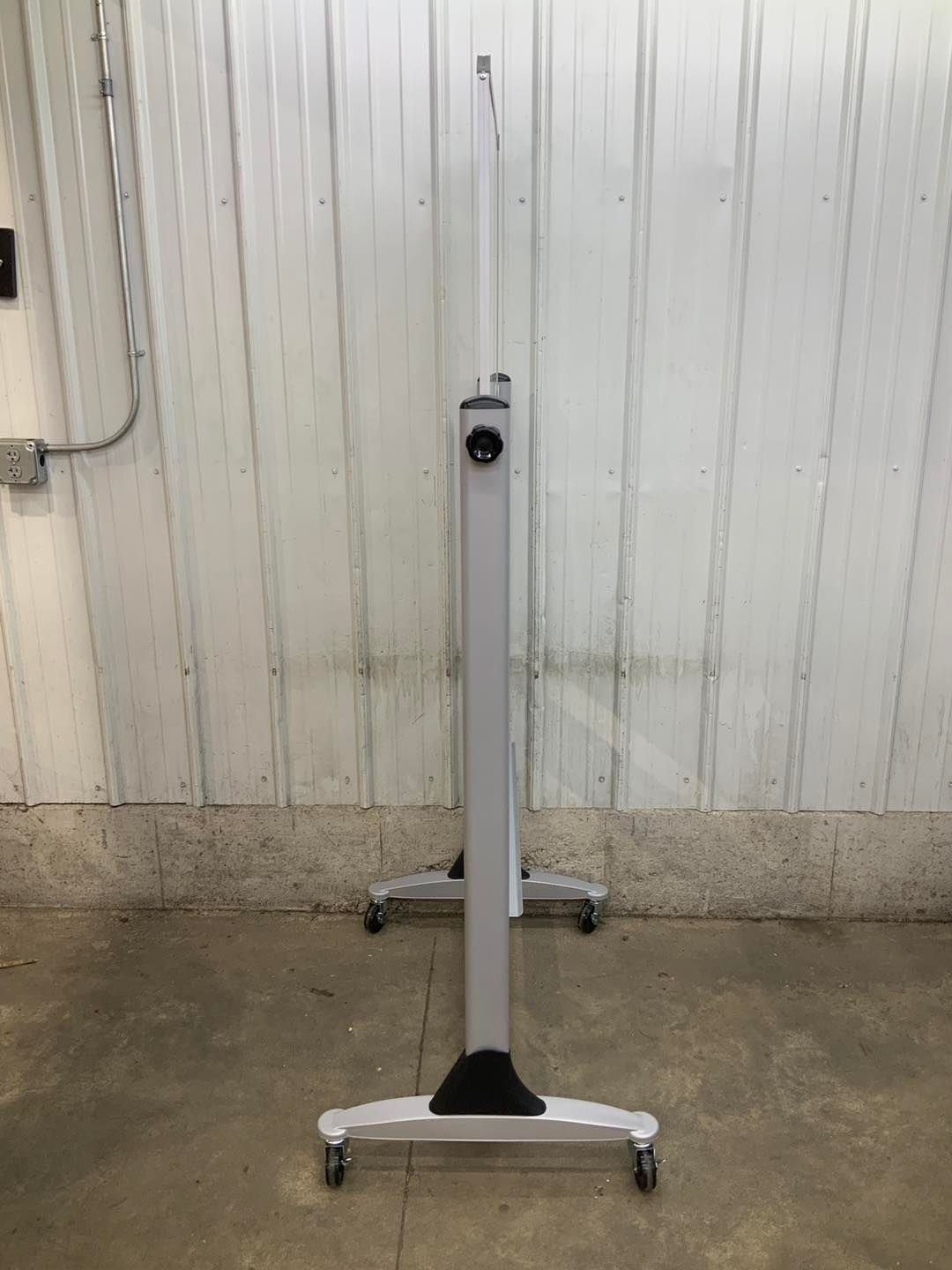 A white table with wheels is sitting on the ground in front of a white wall.