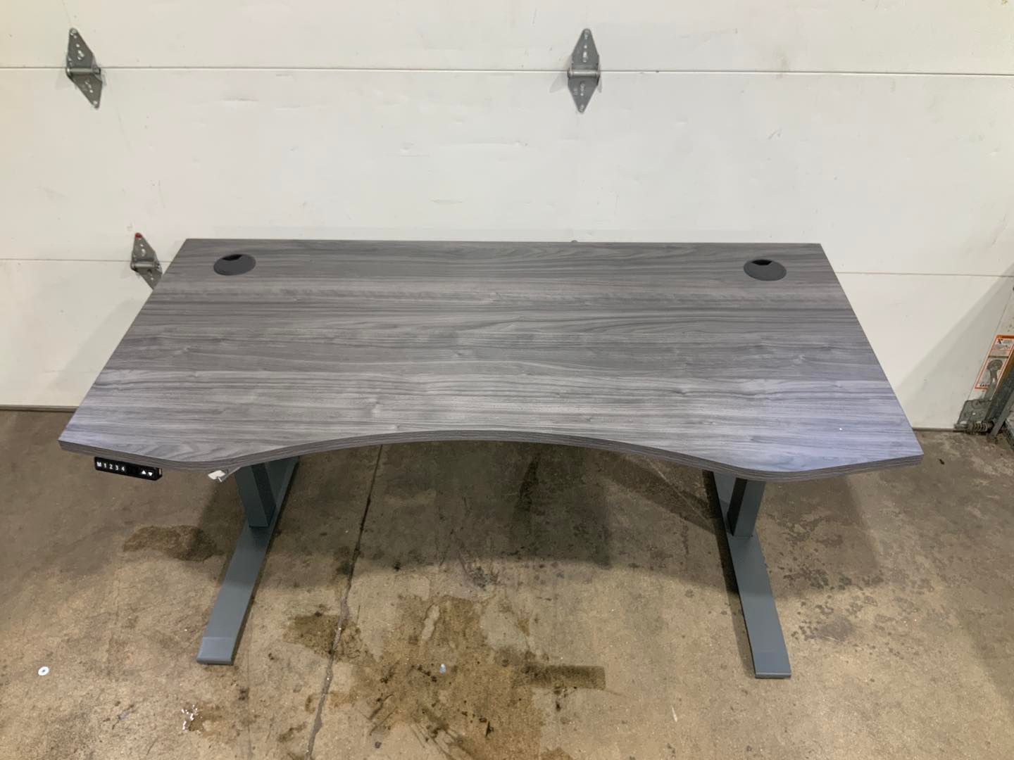 A gray standing desk is sitting in front of a garage door.