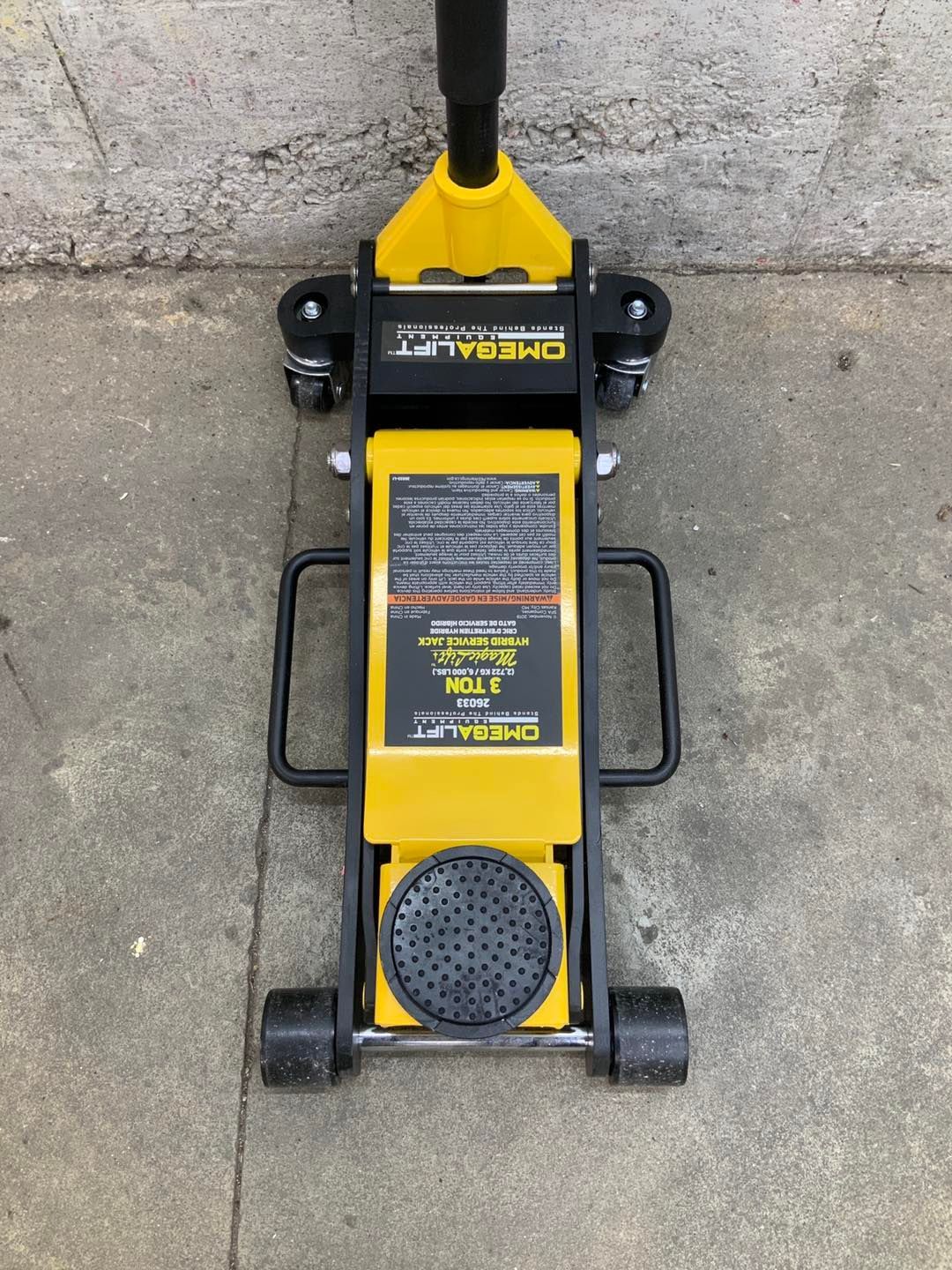 A yellow and black floor jack is sitting on the ground