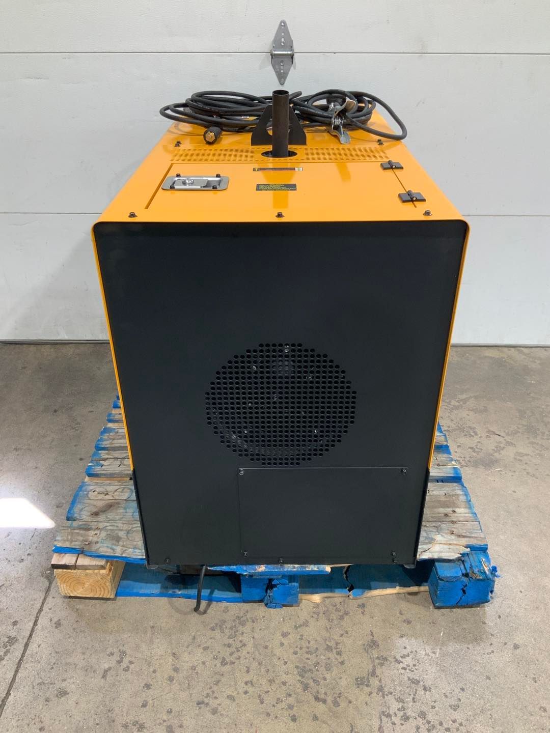 A yellow and black machine is sitting on a blue pallet