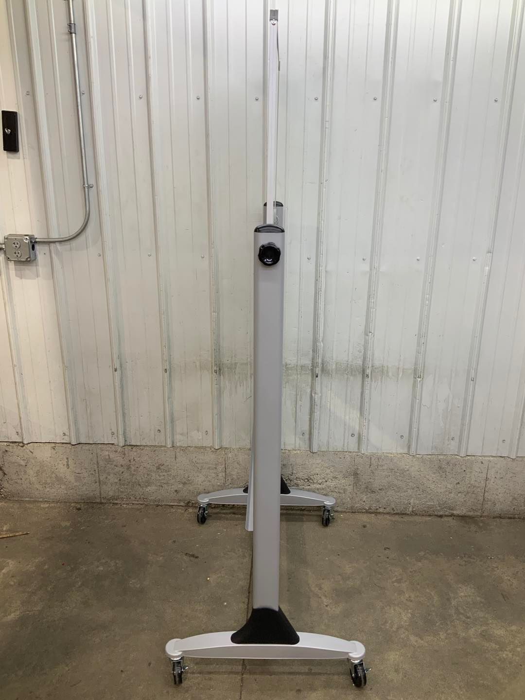 A white table with wheels is sitting in front of a white wall.