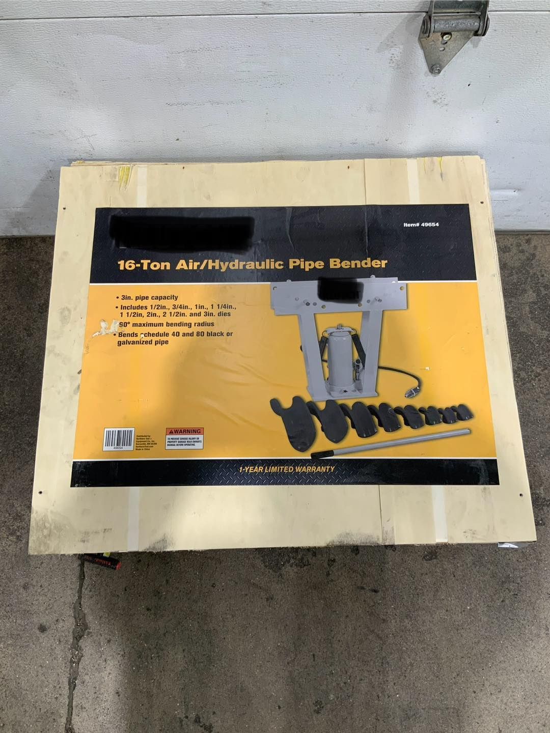 A hydraulic pipe bender is in a wooden box