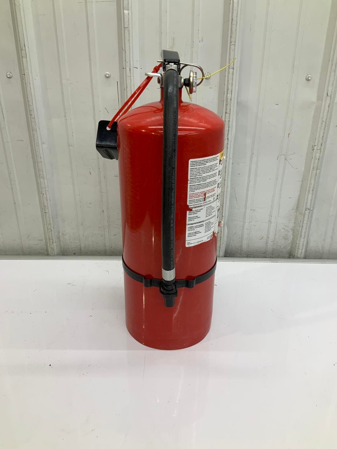 A red fire extinguisher is sitting on a white table.