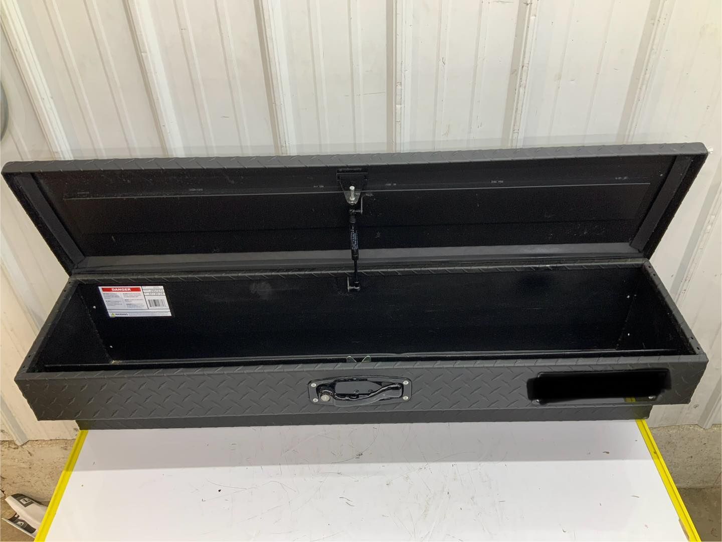 A black toolbox with the lid open is sitting on top of a white table.