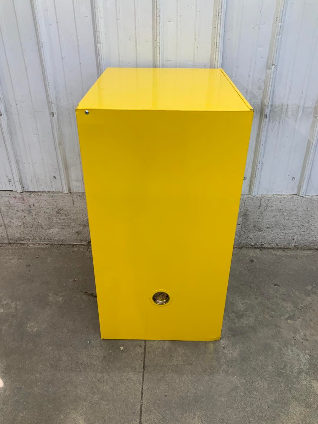A yellow box is sitting on the sidewalk in front of a building.