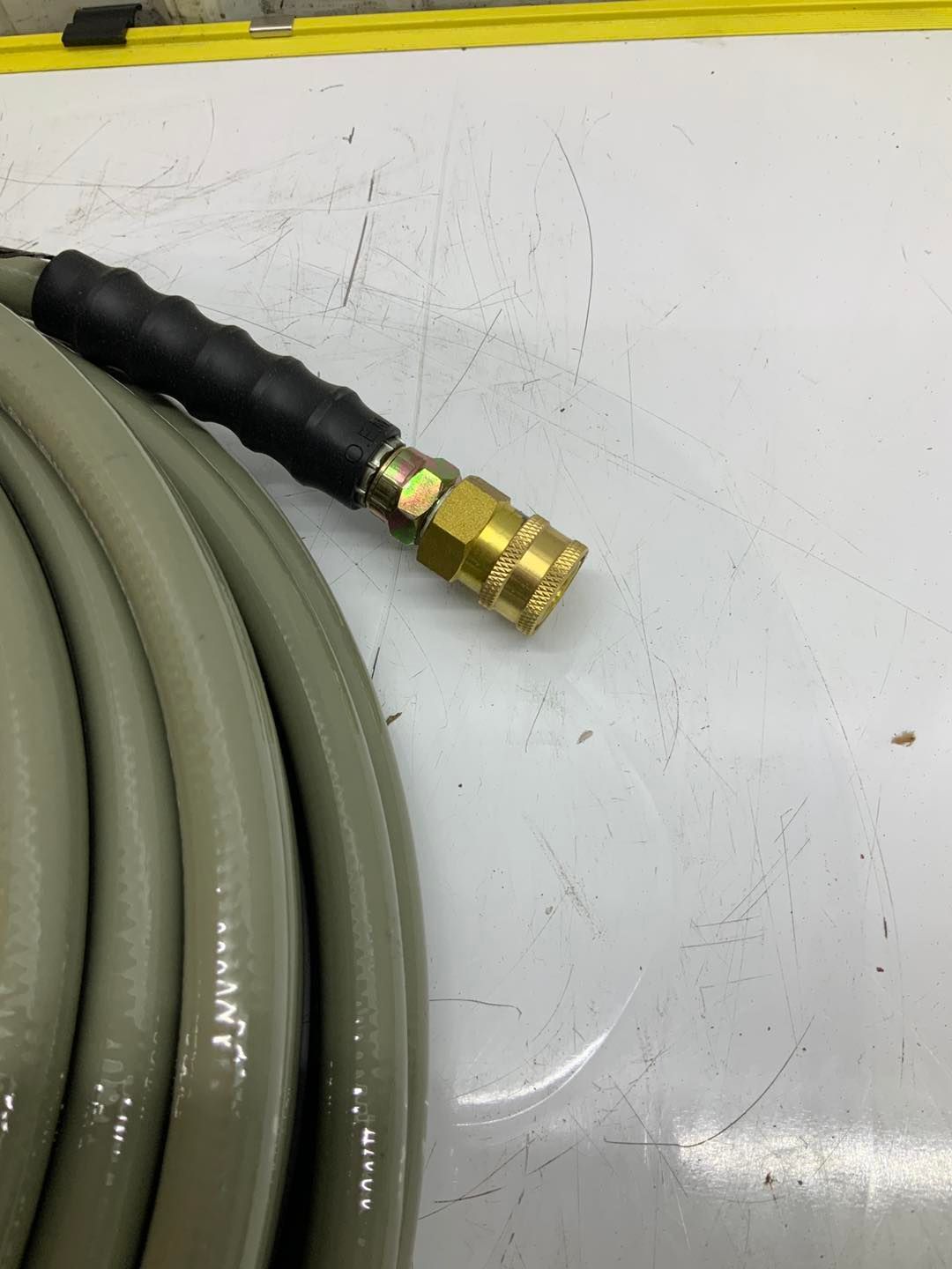 A close up of a hose with a brass connector on a white surface.