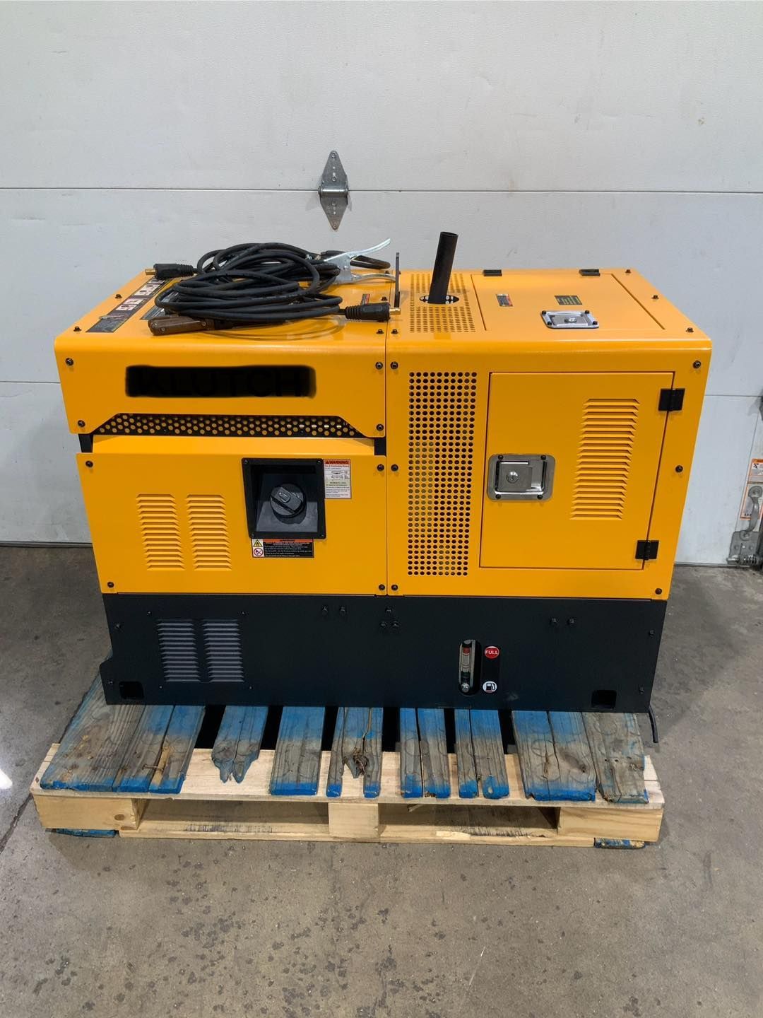 A yellow generator is sitting on top of a wooden pallet.