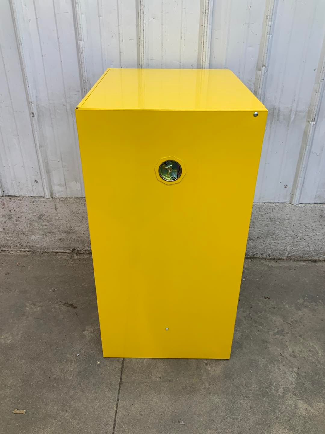 A yellow box is sitting on the sidewalk in front of a building.