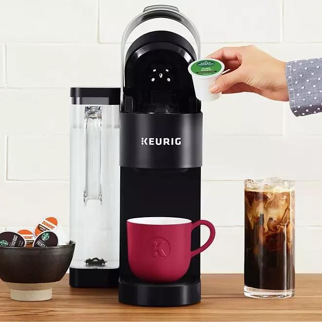 A person is putting a k cup into a keurig coffee maker.