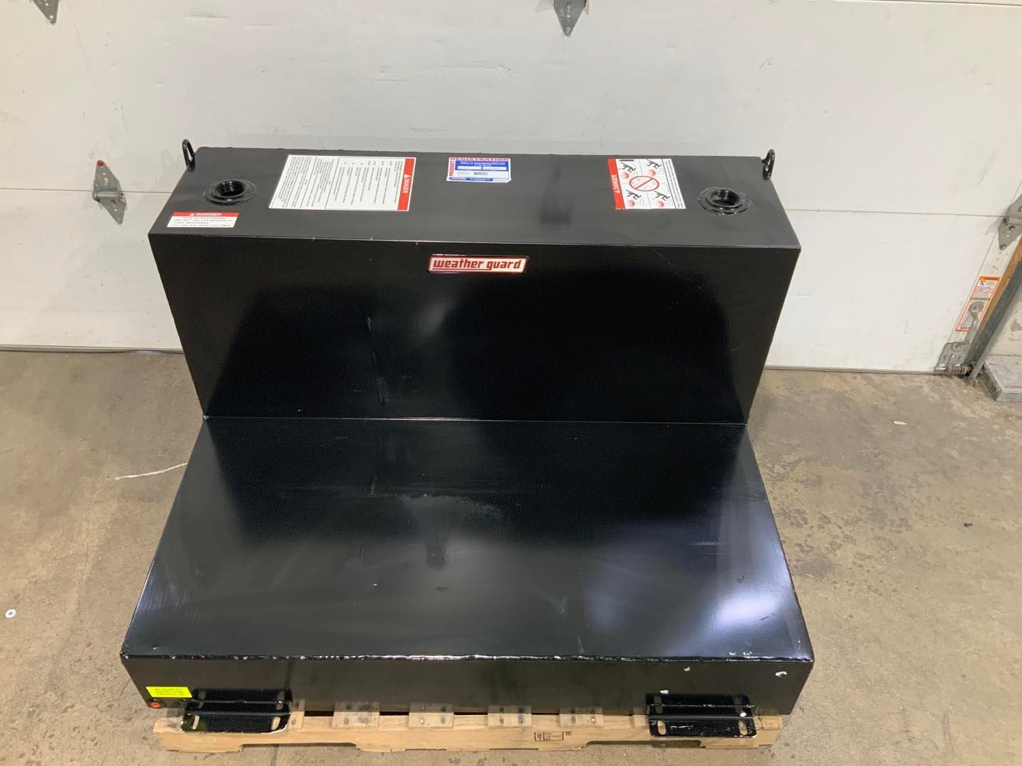 A black tank is sitting on top of a wooden pallet.