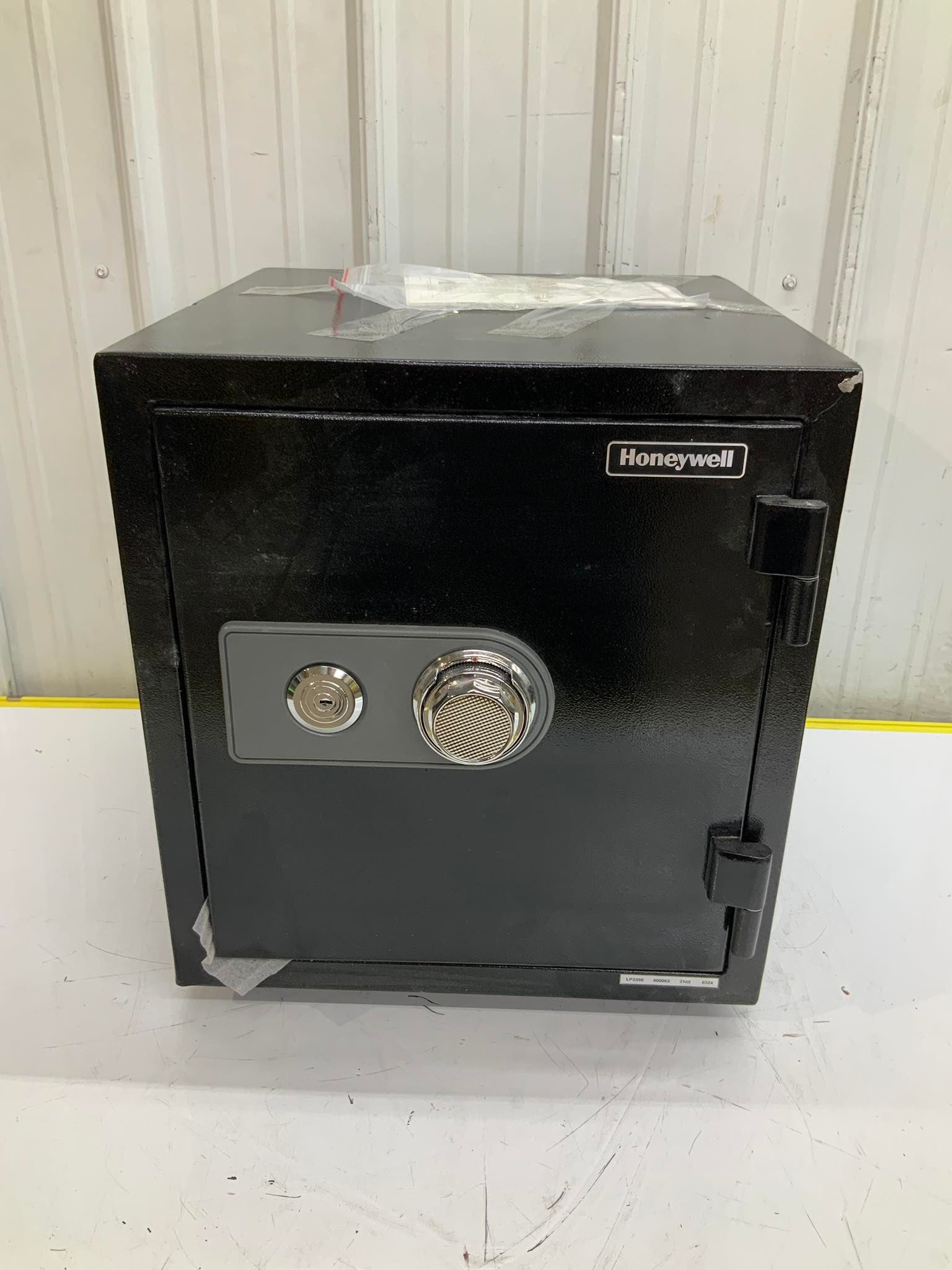 A black safe is sitting on a white table in front of a white wall.