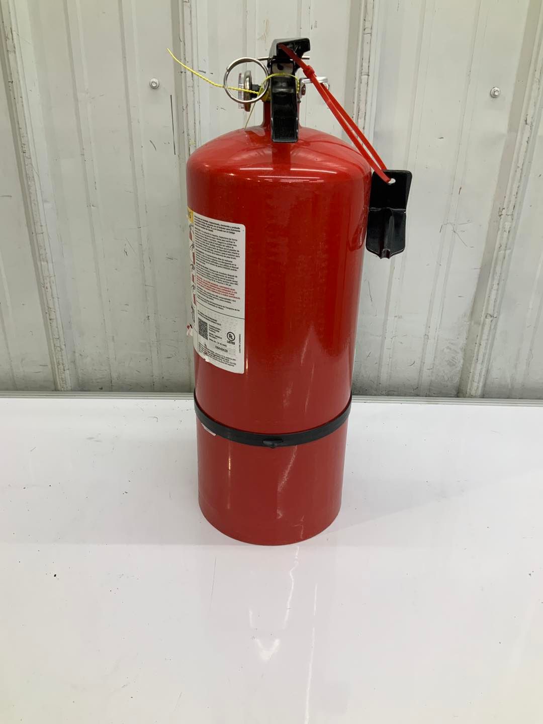 A red fire extinguisher is sitting on a white table.